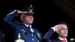 El secretario de Defensa de México, Salvador Cienfuegos (izq) y el presidente Enrique Peña Nieto (der) saludan durante un desfile militar en la Ciudad de México el 16 de septiembre de 2016.