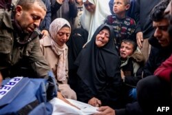 Family and relatives mourn over the body of Palestinian journalist Ahmed Al-Shayah, covered with a press vest, after he was killed during an Israeli strike the previous night in Khan Yunis, Gaza Strip, on Jan. 16, 2025.