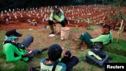 Para petugas penggali kuburan beristirahat di sebuah kompleks pemakaman yang disediakan pemerintah untuk jenazah pasien Covid-19, di Jakarta, 22 April 2020. (Foto: Reuters)
