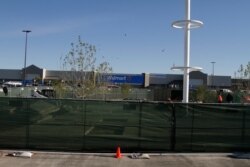 Construction workers stand near a memorial they are building for the 22 people killed at the Cielo Vista Walmart seen in the background, Nov. 14, 2019, in El Paso, Texas, minutes before the store was reopened.
