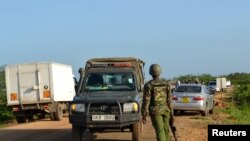 A Kenyan police officer observes motor vehicle traffic near the scene where armed assailants killed three people in the Nyongoro area of Lamu County, Kenya January 2, 2020. 
