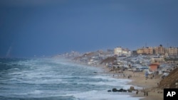 ফাইল- দেইর আল-বালাহতে সমুদ্র সৈকতের পাশে বাস্তুচ্যূত ফিলিস্তিনিদের জন্য নির্মিত একটি শরণার্থী শিবিরের পাশ দিয়ে হাঁটছেন। 