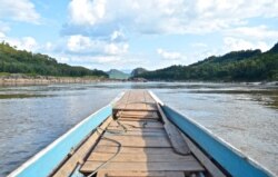 A boat motors down a rocky stretch of the Mekong River in northern Laos in November 2019. (Zsombor Peter/VOA)