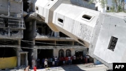 Palestinian Muslim worshipers attend Friday noon prayer beneath the fallen minaret of the al-Susi mosque in Gaza City on Sept. 12, 2014 which was hit by Israeli strikes during the latest round of deadly fighting with Hamas militants. 