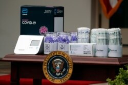 FILE - Materials for COVD-19 testing from Abbott Laboratories, U.S. Cotton, and Puritan are displayed as President Trump speaks about the coronavirus during a press briefing in the Rose Garden of the White House, May 11, 2020, in Washington.