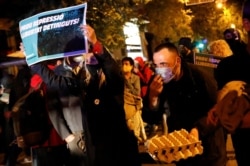 A woman holds a sign during a protest against police raids and the arrest of Catalan separatists, in Barcelona, Spain, Oct. 28, 2020.