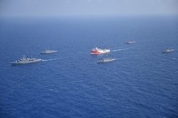 FILE - Turkish seismic research vessel Oruc Reis is escorted by Turkish Navy ships as it sets sail in the Mediterranean Sea, off Antalya, Turkey, Aug. 10, 2020.