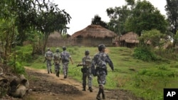 FILE - Myanmar Border Guard officers walk along a path in Tin May village, Rakhine state, Myanmar, July 14, 2017. The Myanmar military has filed suit over what it says was a false report of military shelling having killed two Muslim women in Rakhine.