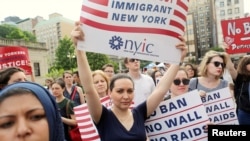 FILE - Protesters hold signs against U.S. President Donald Trump's limited travel ban, approved by the U.S. Supreme Court, in New York City, June 29, 2017.