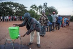 FILE - People queue to wash their hands as a preventive measure against the spread of the COVID-19 coronavirus before they can queue again to vote at a polling station in Lilongwe, June 23, 2020.