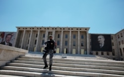 A security officer patrols as Turkey's President Recep Tayyip Erdogan attends a ceremony at the parliament building decorated with the portraits of Turkey's founder Mustafa Kemal Ataturk, right, and Erdogan, in Ankara, July 15, 2021.