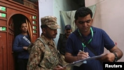 A census enumerator, right, along with a Pakistan Army soldier notes details outside a house during Pakistan’s sixth population census in Karachi, Pakistan March 15, 2017.
