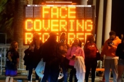 A sign encourages visitors to wear face masks amid the COVID-19 pandemic Feb. 19, 2021, in Santa Monica, Calif.
