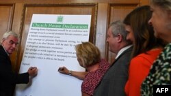 Britain's opposition Labour Party's shadow Chancellor John McDonnell, left, signs a cross-party declaration during an event with representatives of Britain's other pro-EU political parties, to discuss Brexit, in London, Aug. 27, 2019.