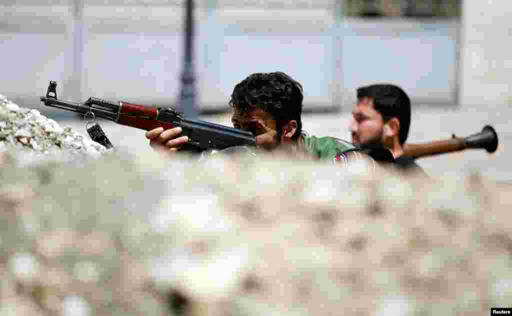 Dua Tentara Pembebasan Suriah di belakang barikade di sebuah jalan di Aleppo (13/8).