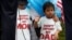 FILE - Boys wearing T-shirts calling for their parents not to be deported stand during a rally by immigration activists in Washington, D.C., Aug. 15, 2017. 
