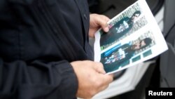 A German policeman holds the picture of a terrorist-subject infront of the main terminal of Berlin-Schoenefeld airport, in Schoenefeld, near Berlin, Oct. 9, 2016.