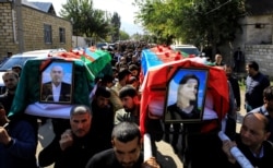 People carry the coffins of Anar Aliyev and his wife Nurcin Aliyeva, killed in Ganja attack during the fighting over the breakaway region of Nagorno-Karabakh, in the city of Shamkir, Azerbaijan, Oct. 12, 2020.