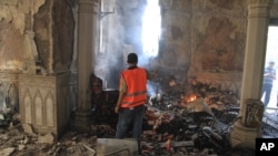 An Egyptian takes video of the burning remains of the Rabaah al-Adawiya mosque, in the center of the largest protest camp of Morsi supporters that was cleared by security forces, Nasr city, Cairo, August 15, 2013. 