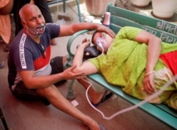 Mukesh Bhardwaj cries next to his wife, who receives oxygen support outside a Gurudwara (Sikh temple) in Ghaziabad, India, May 3, 2021.