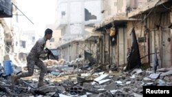 A Shi'ite fighter, fighting along forces loyal to Syria's President Bashar al-Assad, carries his weapon as he runs along a deserted street in Hujaira town, south of Damascus, Nov. 20, 2013. 