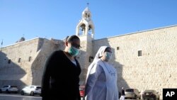 Umat ​​Kristen berjalan menuju Gereja Nativity yang dibuka kembali untuk pengunjung setelah hampir tiga bulan ditutup karena pandemi coronavirus, di Betlehem, Tepi Barat, Selasa, 26 Mei 2020. (Foto AP / Mahmoud Illean)