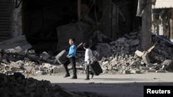 Dua bocah Suriah berjalan di jalan yang penuh dengan puing-puing di Deir al-Zor, Suriah Timur, 6 Februari 2014 (Foto:dok) 