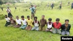 FILE - Ten Rohingya Muslim men with their hands bound kneel as members of the Myanmar security forces stand guard in Inn Din village, Sept. 2, 2017. 