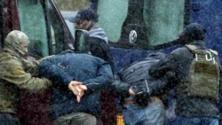 FILE - Law enforcement officers detain two men as opposition supporters rally to protest against police violence and the Belarus presidential election results in Minsk, Nov. 29, 2020.