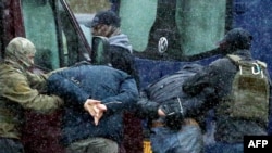 FILE - Law enforcement officers detain two men as opposition supporters rally to protest against police violence and the Belarus presidential election results in Minsk, Nov. 29, 2020.