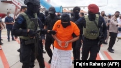Polisi mengawal Zulkarnaen, seorang pemimpin senior Jemaah Islamiyah (JI) yang terkait dengan Al-Qaeda, yang sedang dalam pelarian karena perannya dalam Bom Bali 2002, di Bandara Internasional Soekarno-Hatta, 16 Desember 2020. (Foto: AFP/Fajrin Raharjo)