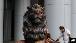 A worker cleans the iconic lion statue in front of the international HSBC Bank branch that was painted with red paint in Hong Kong, Jan. 2, 2020. 