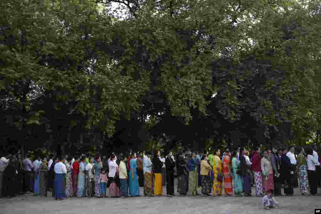 People stand outside a polling station in Mandalay, Nov. 8, 2015.