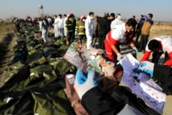 FILE - A rescue worker shows pictures of a girl recovered from a Ukrainian plane crash site in Shahedshahr, southwest of the capital Tehran, Iran.