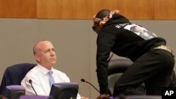 Stevante Clark jumps on the dais and shouts at Sacramento Mayor Darrell Steinberg, left, during a city council meeting in Sacramento, California, March 27, 2018. 