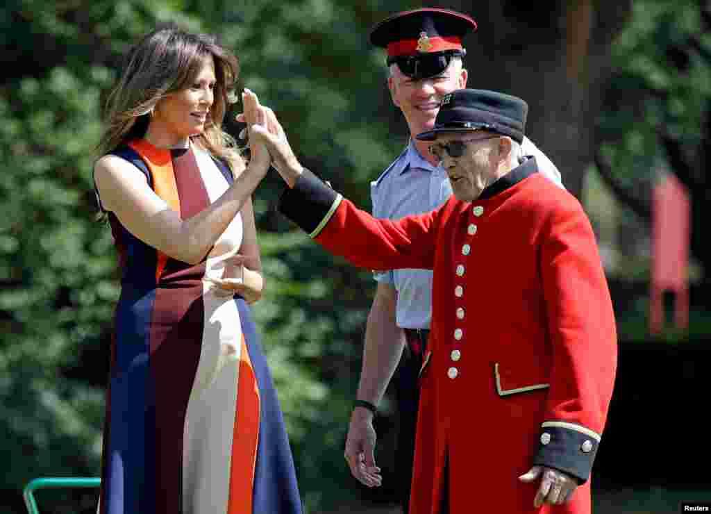 U.S. First Lady Melania Trump high-fives with a British military veteran known as a "Chelsea Pensioner" during a game of bowls at The Royal Hospital Chelsea in central London, England.