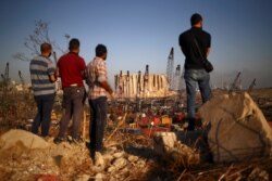 FILE - People view the damaged site of Tuesday's blast in Beirut's port area, Lebanon, Aug. 7, 2020.