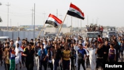 Volunteers, who have joined the Iraqi army to fight against militants from the radical Islamic State of Iraq and the Levant (ISIL), carry weapons and wave Iraqi flags during a parade in the streets of eastern Baghdad June 15, 2014.