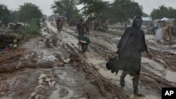 People trudge along the main passageway through United Nations' Malakal Camp for Internally Displaced People, (IDP) during the wet season which has made life for hundreds of thousands of IDPs in South Sudan very challenging, in Malakal, July 24, 2014.