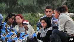 Residents of La Gabriela neighborhood who lost their homes when a landslide buried some 30 houses and trapped dozens beneath mud and rubble following weeks of drenching rains, rest while rescue workers search for survivors in Bello, northwestern Colombia,