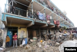 Orang-orang Palestina memeriksa kerusakan di sebuah sekolah di kamp Nuseirat di Jalur Gaza yang dijadikan tempat penampungan pengungsi di tengah perang antara gerakan Hamas Palestina dan Israel, 14 Mei 2024. (Foto: Ramadan Abed/Reuters)