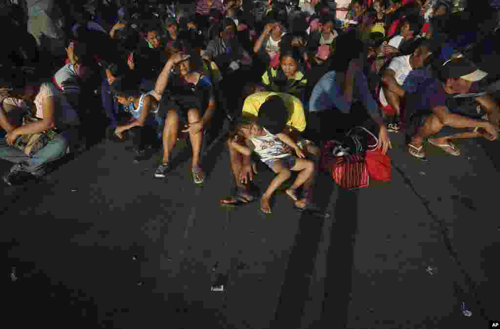 Survivors of Typhoon Haiyan shade themselves from the rising sun after spending the night on the tarmac in the airport in Tacloban, where they wait to be evacuated, Nov. 15, 2013.