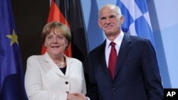 German Chancellor Angela Merkel and the Prime Minister of Greece, Georgios Papandreou shake hands prior to a dinner at the chancellery in Berlin, Germany, Sept. 27, 2011.