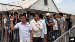 FILE - In this file photo taken on Monday, June 13, 2016, migrants who live in the Hellenikon refugee and migrant camp in Athens wait to register for asylum. A government official in Athens on Wednesday, Aug. 3, 2106 said to the Associated Press that there is no sign yet that a deal between the European Union and Turkey to stop migrants coming to Europe has faltered since the attempted military coup in the country.