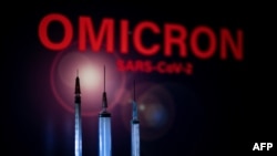 FILE- This photo taken in Toulouse, southwestern France, on December 1, 2021 shows syringes and a screen displaying Omicron, the name of the new covid 19 variant. 