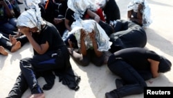 FILE - Migrants sit at a naval base after being rescued by Libyan coast guards, in Tripoli, Libya, June 18, 2018. Libya's navy said Friday it rescued 213 migrants off the Mediterranean coast.