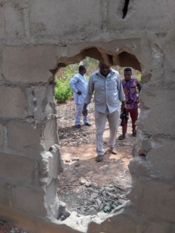 People inspect the broken perimeter wall through which gunmen gained access the male and female hostels at the Federal College in Kaduna, Nigeria, March 12, 2021.