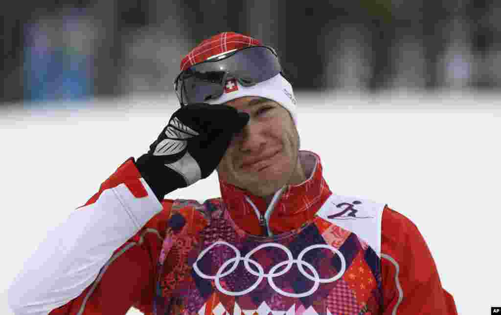Dario Cologna dari Swiss menangis di podium setelah memenangkan medali emas dalam skiaton cross-country 30 kilometer di Krasnaya Polyana, Rusia (9/2). (AP/Gregorio Borgia)