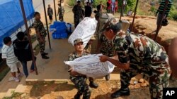 Nepalese soldiers load U.S. AID relief sacks at a staging area near Saturday's massive earthquake's epicenter in the town of Gorkha, Nepal, April 28, 2015. 