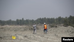 FILE - Construction workers walk along the island of Bhasan Char in the Bay of Bengal, Bangladesh, Feb. 14, 2018.